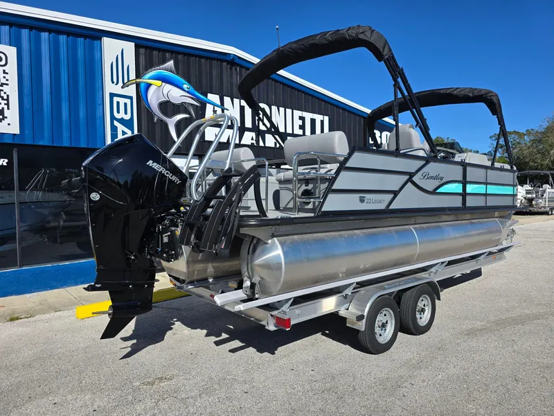 Slide: The Image of 2025 Bentley Pontoons 223 Quad Swingback Legacy Tritoon on trailer, parked outside dealership. - 2