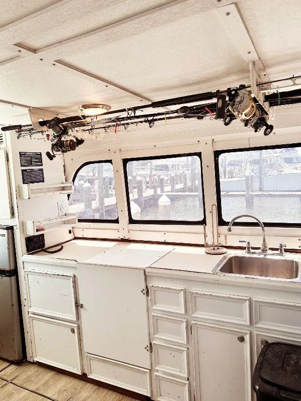 Slide: The Image of 1975 Hatteras 36 Convertible interior with fishing rods, white cabinets, and sink. - 15