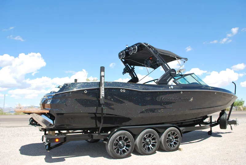 Slide: The Image of 2024 MasterCraft X26 boat on trailer under clear blue sky. - 2