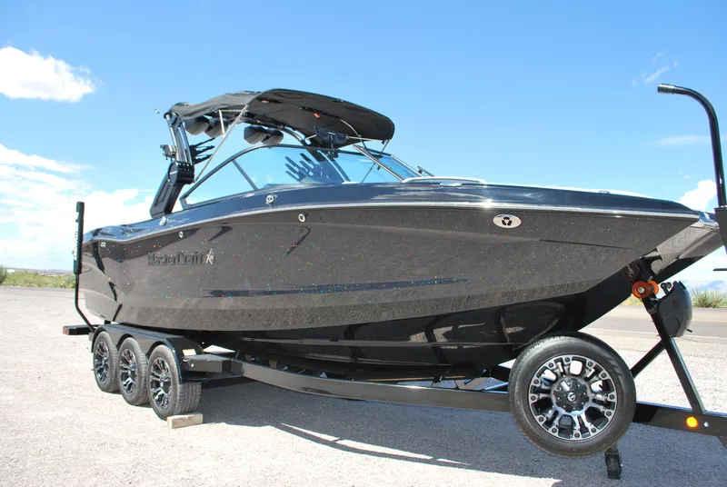Slide: The Image of 2024 MasterCraft X26 boat on trailer under clear blue sky. - 3