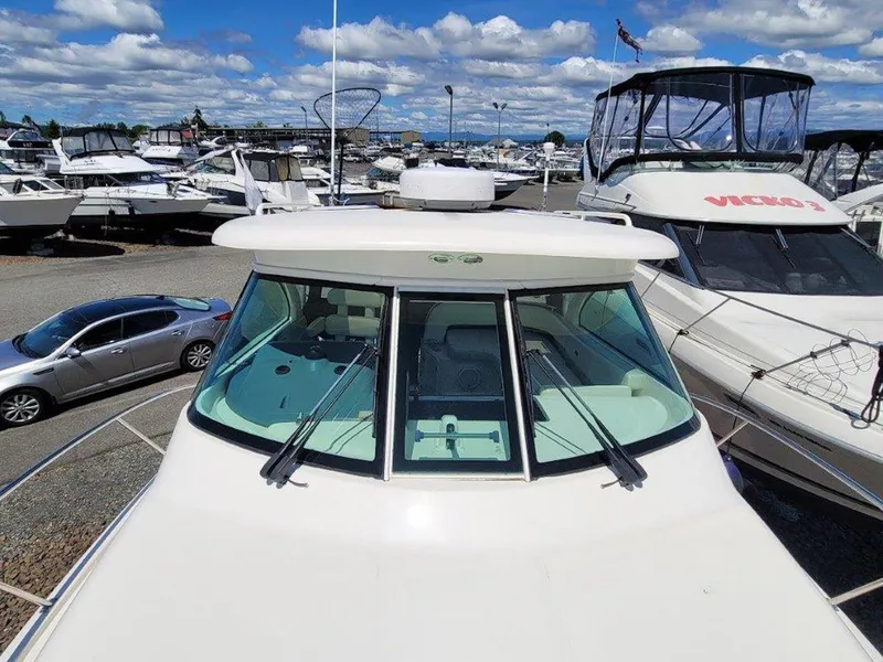 Slide: The Image of 2013 Pursuit 345 OS Offshore boat at marina, surrounded by other vessels and a car. - 8
