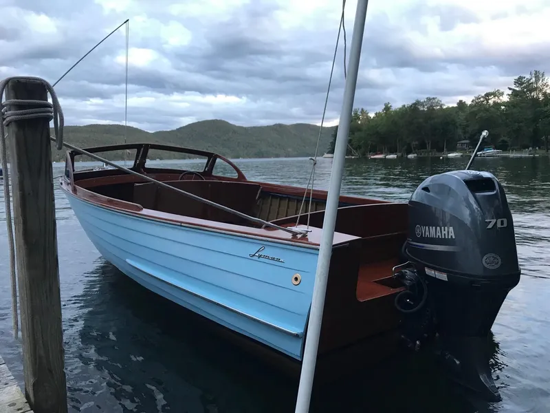 Slide: The Image of 1956 Lyman 18 Outboard boat with Yamaha motor docked on a serene lake. - 12
