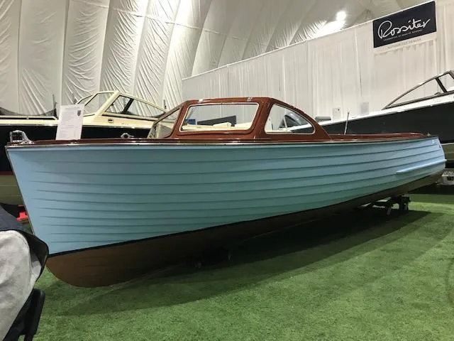 Slide: The Image of 1956 Lyman 18 Outboard boat with light blue hull on display indoors. - 2