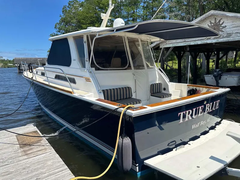 Slide: The Image of 2005 Sabre 42 Express boat docked, named "True Blue," with a sleek design and spacious deck. - 20