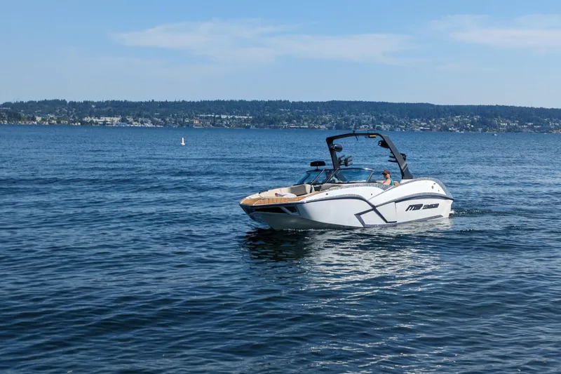 Slide: The Image of 2025 MB B52 25 Alpha boat cruising on a serene lake under a clear blue sky. - 3