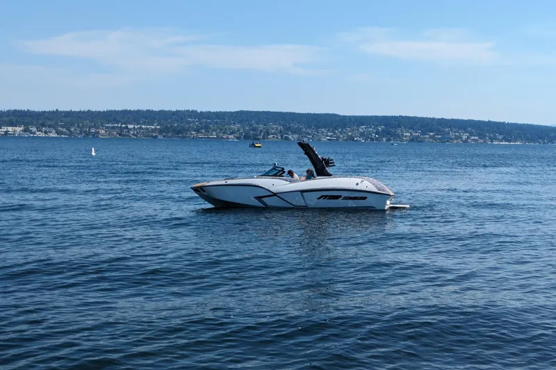 Slide: The Image of 2025 MB B52 25 Alpha boat cruising on a serene lake under a clear blue sky. - 5