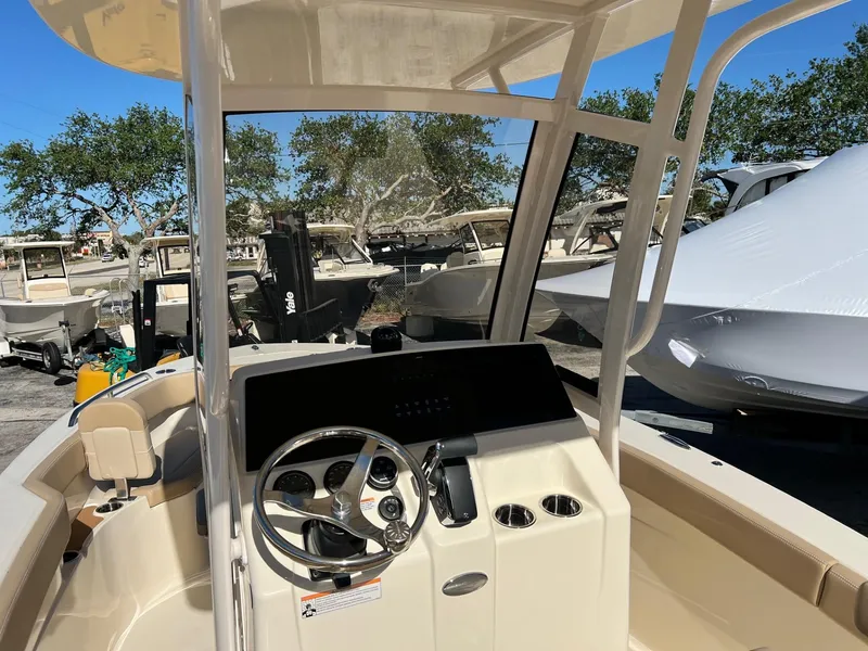 Slide: The Image of 2024 Scout 215 XSF boat interior with steering wheel and console, parked outdoors. - 4