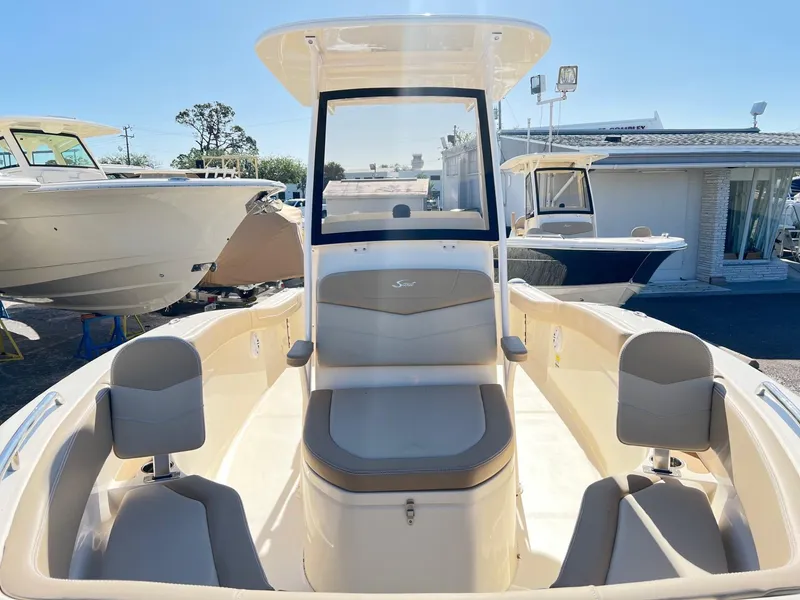 Slide: The Image of 2024 Scout 215 XSF boat interior with seating and console, docked outdoors. - 8