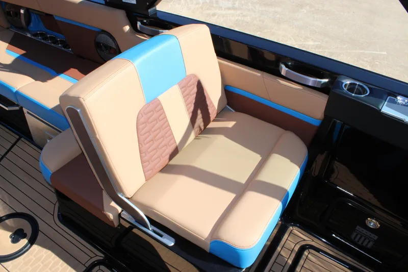 Slide: The Image of 2023 MasterCraft X26 boat interior with tan and blue seating, cup holders, and sleek design. - 17