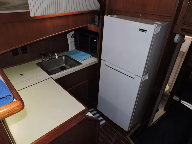 Slide: The Image of Compact kitchen area in a 1990 Post 44 boat with sink and refrigerator. - 27