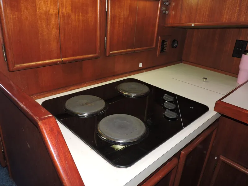 Slide: The Image of 1990 Post 44 yacht kitchen with electric stovetop and wooden cabinetry. - 28