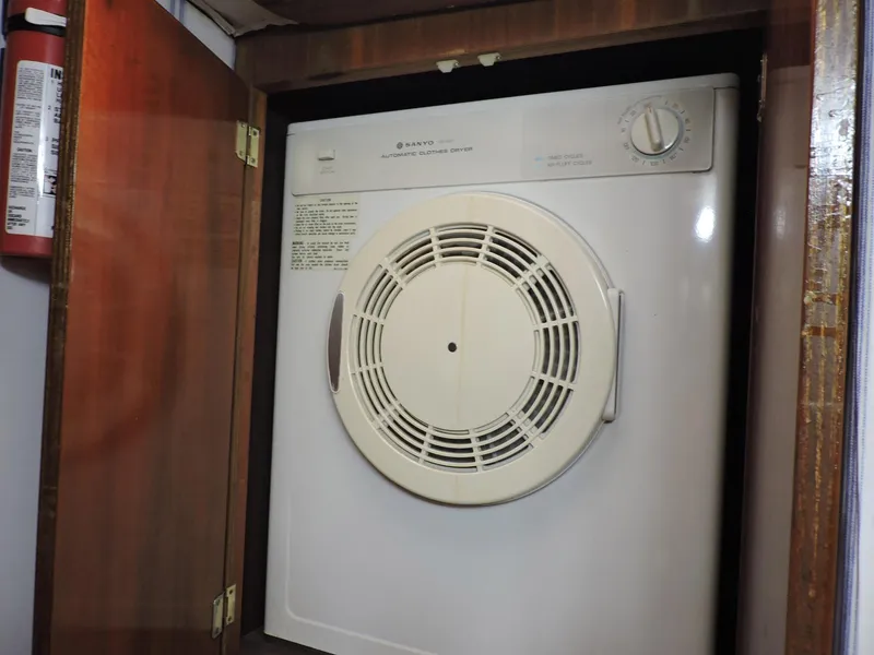 Slide: The Image of Dryer inside 1990 Post 44 Sport Fisherman boat, wooden cabinet, fire extinguisher nearby. - 49