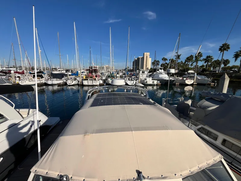Slide: The Image of 2005 Mainship RumRunner docked in a marina with sailboats and palm trees. - 19