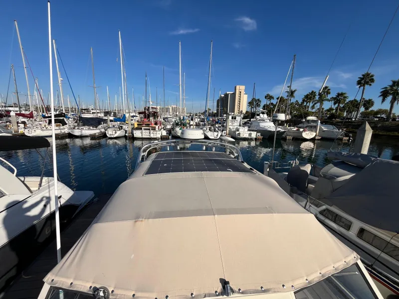 Slide: The Image of 2005 Mainship RumRunner docked in a marina with sailboats and palm trees. - 20