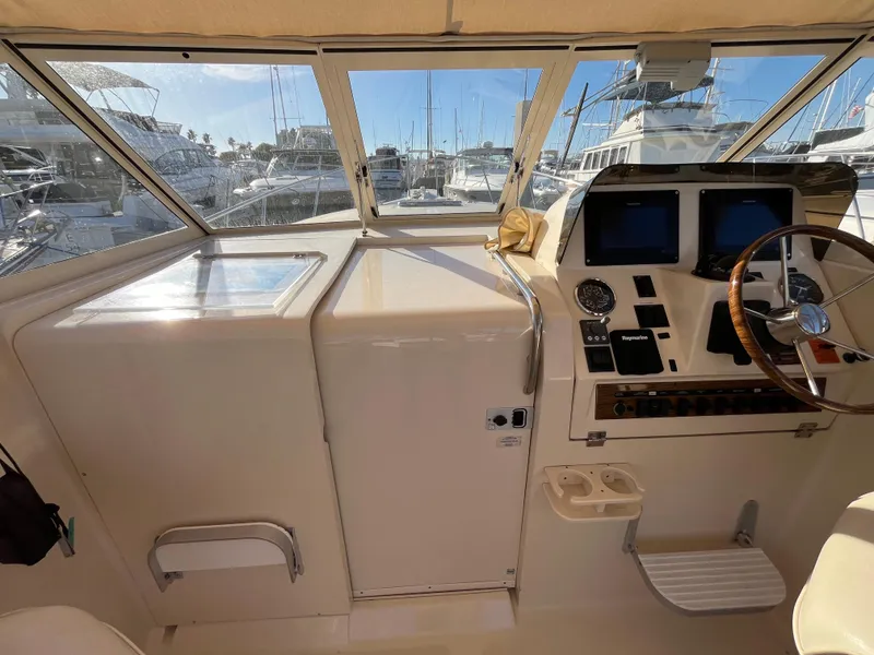 Slide: The Image of 2005 Mainship RumRunner helm with navigation instruments and marina view. - 21