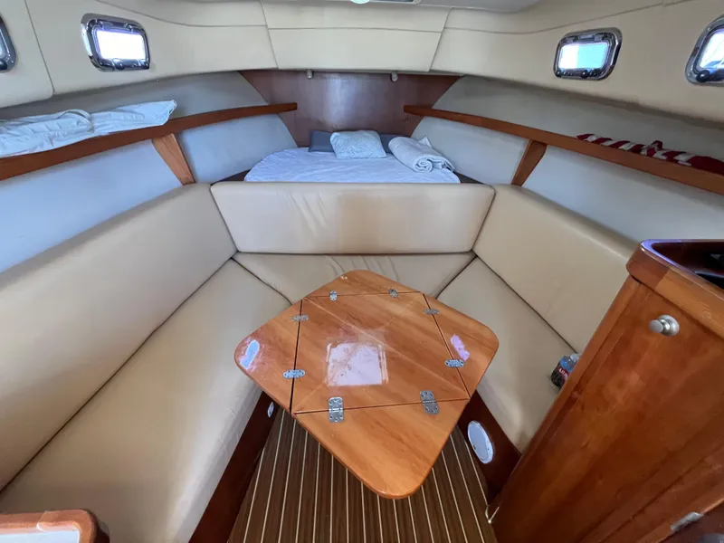 Slide: The Image of 2005 Mainship RumRunner cabin interior with beige seating and wooden table. - 25