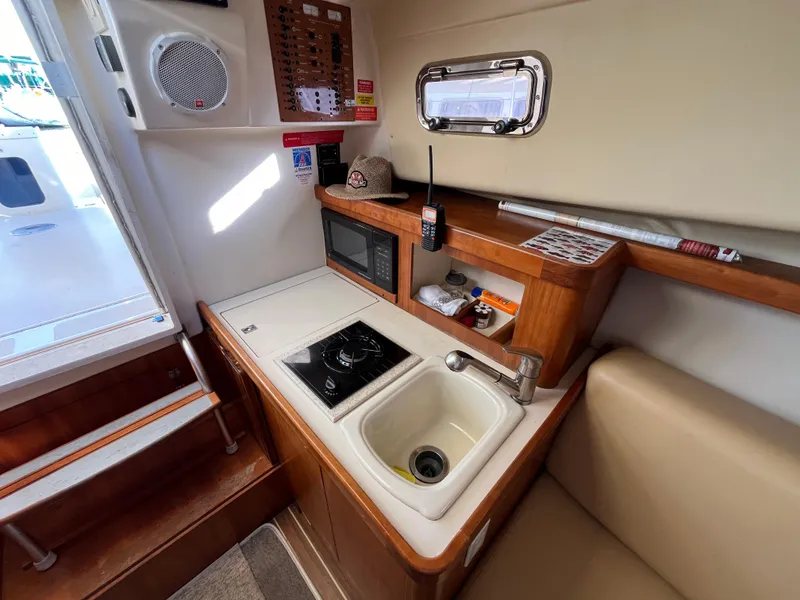 Slide: The Image of 2005 Mainship RumRunner galley with sink, stove, and microwave in compact, efficient layout. - 26