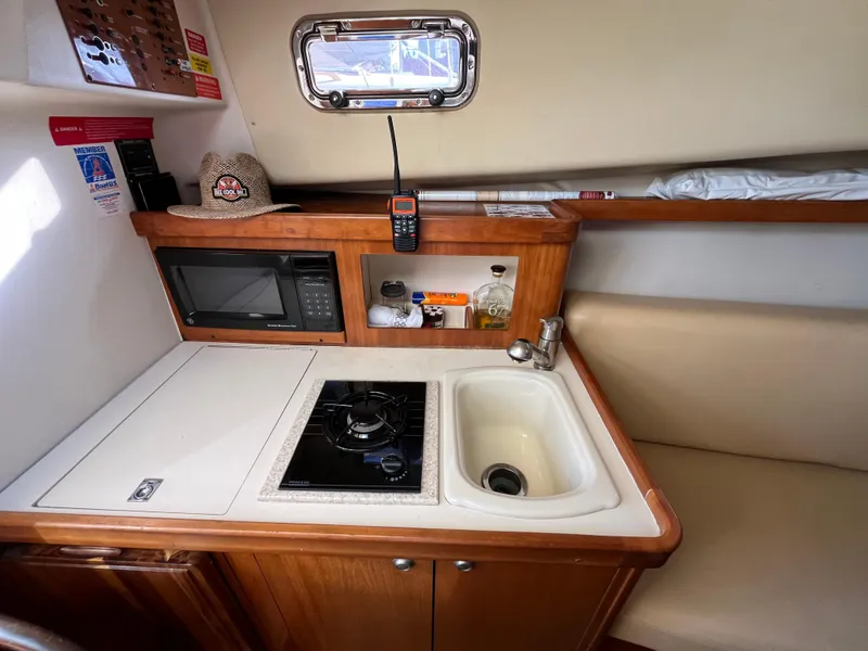 Slide: The Image of 2005 Mainship RumRunner galley with stove, sink, and microwave. - 27