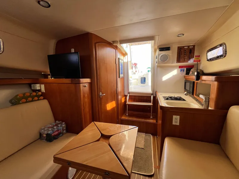 Slide: The Image of 2005 Mainship RumRunner interior with cozy seating, kitchenette, and TV. - 30