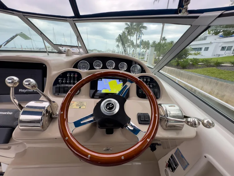 Slide: The Image of 2005 Sea Ray 340 Sundancer helm with wood steering wheel and navigation controls. - 26