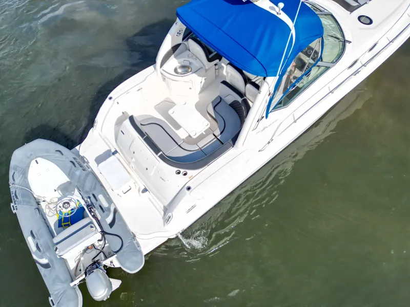 Slide: The Image of 2005 Sea Ray 340 Sundancer with blue canopy and attached dinghy on water. - 37