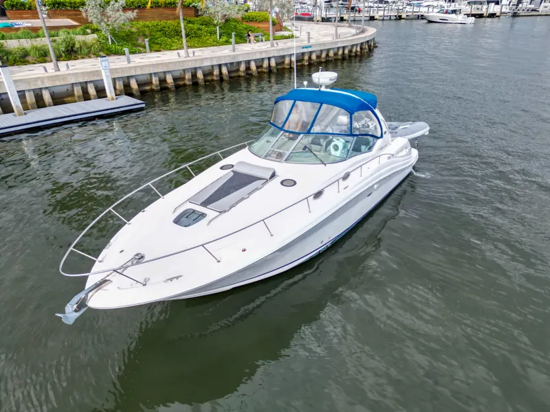 Slide: The Image of 2005 Sea Ray 340 Sundancer yacht docked in a marina, featuring a sleek design and blue canopy. - 6