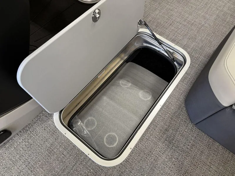 Slide: The Image of 2025 Barletta C22M boat storage compartment with open lid on carpeted floor. - 13