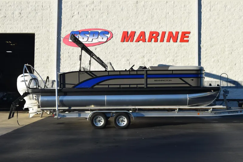 The Image of 2025 Bennington 23 SSBSE pontoon boat on trailer outside marine dealership. - 1