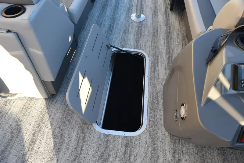 Slide: The Image of 2025 Bennington 23 SSBSE boat interior with open storage compartment on carpeted floor. - 16