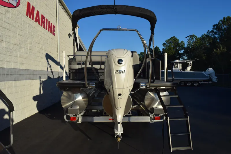 Slide: The Image of 2025 Bennington 23 SSBSE pontoon boat with outboard motor, parked at a marine dealership. - 4