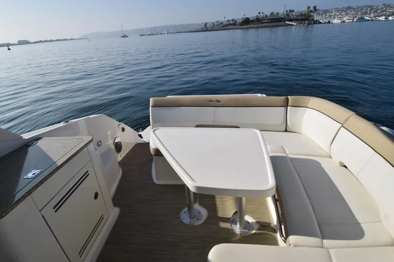Slide: The Image of 2014 Sea Ray 350 Sundancer boat interior with seating and table on calm water. - 29