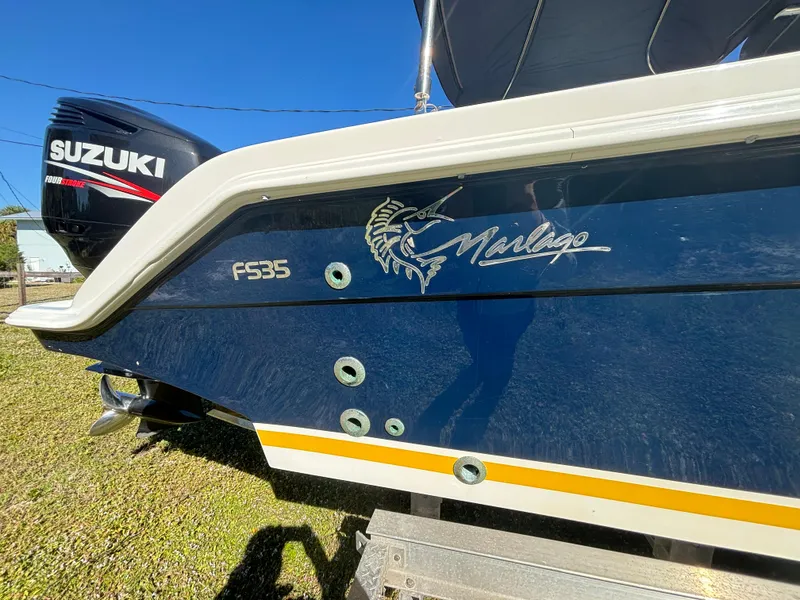 Slide: The Image of 2002 Marlago 35 FS boat with Suzuki engine, blue hull, and marlin logo. - 12