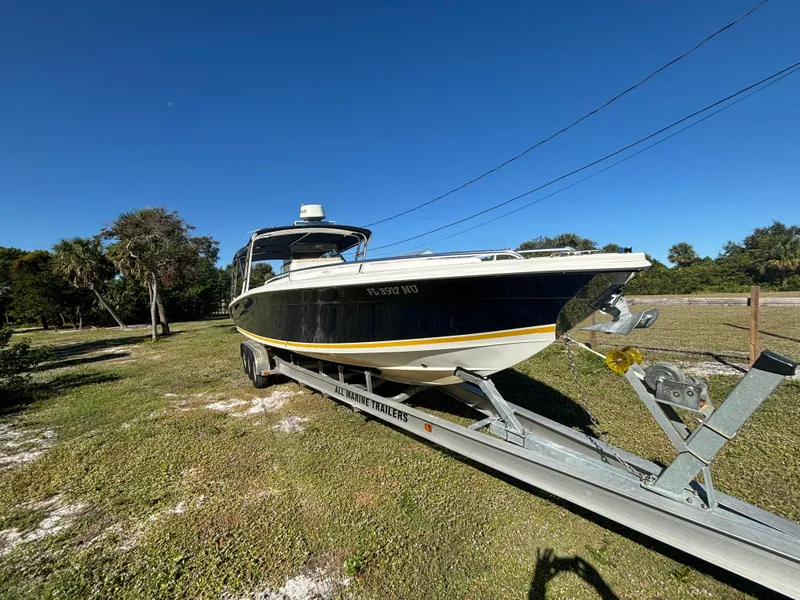 Slide: The Image of 2002 Marlago 35 FS boat on trailer, parked on grassy area under clear blue sky. - 4