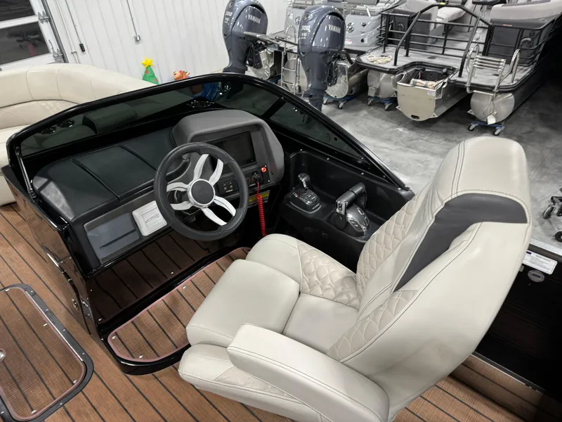 Slide: The Image of 2023 Manitou 25 LX Twin SHP boat interior with steering wheel and captain's chair. - 12