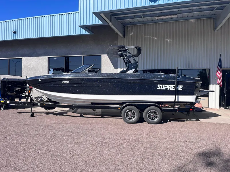 Slide: The Image of 2025 Supreme S240 boat on trailer outside a building. - 1