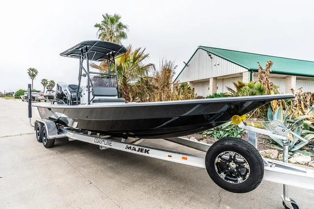 Slide: The Image of 2024 Majek Boats 25 XTREME on trailer, parked outdoors near palm trees and a building. - 5