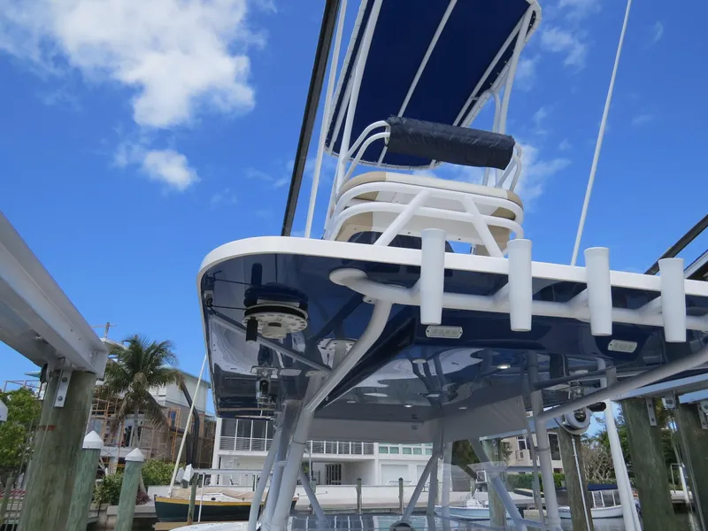 Slide: The Image of 2015 Invincible 42 Open Fisherman boat with blue canopy and seating, docked under clear sky. - 14