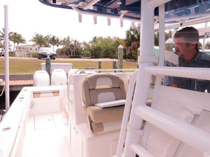 Slide: The Image of 2015 Invincible 42 Open Fisherman boat with seating and controls, docked near palm trees. - 15