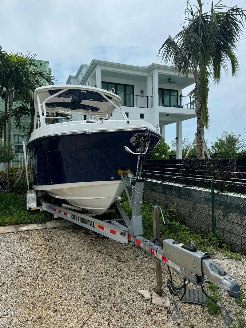 Slide: The Image of 2016 Century 24 Resorter boat on trailer, parked near modern house and palm trees. - 2