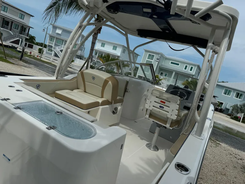 Slide: The Image of 2016 Century 24 Resorter boat interior with seating and helm, parked near coastal homes. - 5