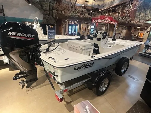 Slide: The Image of 2025 Mako Pro Skiff 15 CC boat with Mercury engine on display indoors. - 1