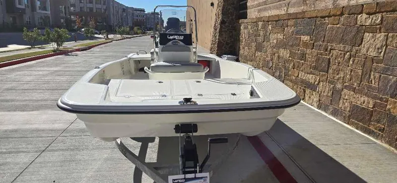Slide: The Image of 2025 Mako Pro Skiff 15 CC boat on trailer, parked on urban street. - 2
