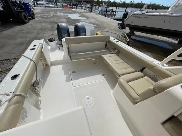 Slide: The Image of 2018 Pursuit 265 DC boat interior with seating and twin engines at a marina. - 13