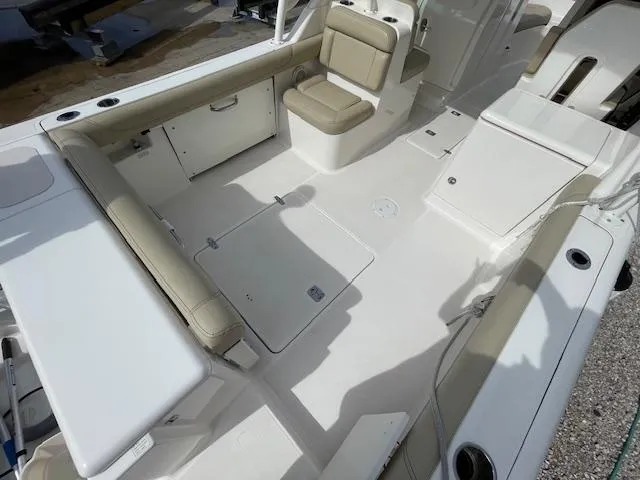Slide: The Image of 2018 Pursuit 265 DC boat interior with beige seating and storage compartments. - 15