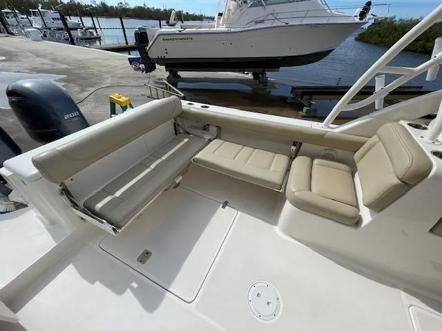 Slide: The Image of 2018 Pursuit 265 DC boat interior with beige seating, docked by the water. - 16