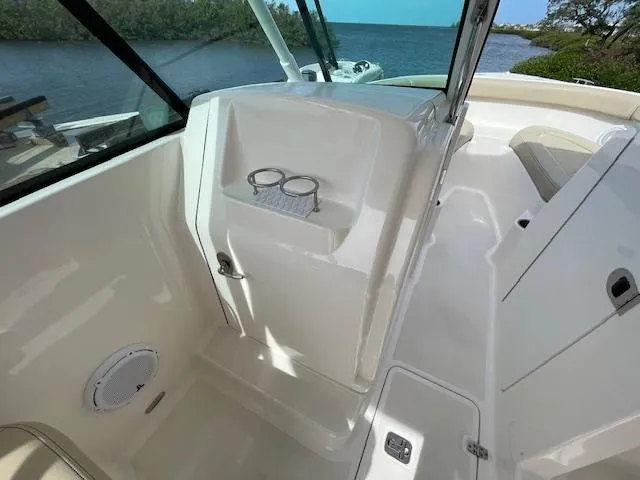 Slide: The Image of 2018 Pursuit 265 DC boat interior with cup holders and seating, near water. - 18