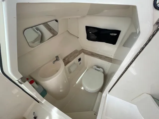 Slide: The Image of 2018 Pursuit 265 DC boat interior bathroom with sink, toilet, and mirror. - 21
