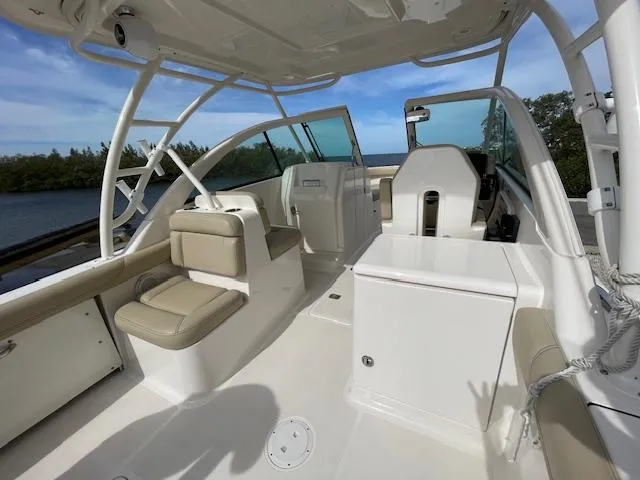Slide: The Image of 2018 Pursuit 265 DC boat interior with seating and helm, on a sunny day. - 26