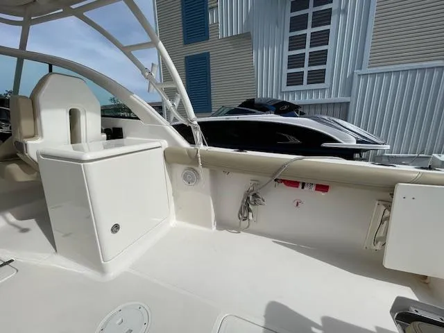 Slide: The Image of 2018 Pursuit 265 DC boat interior with seating and storage, docked near modern buildings. - 27