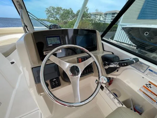 Slide: The Image of 2018 Pursuit 265 DC boat dashboard with steering wheel and navigation controls. - 32